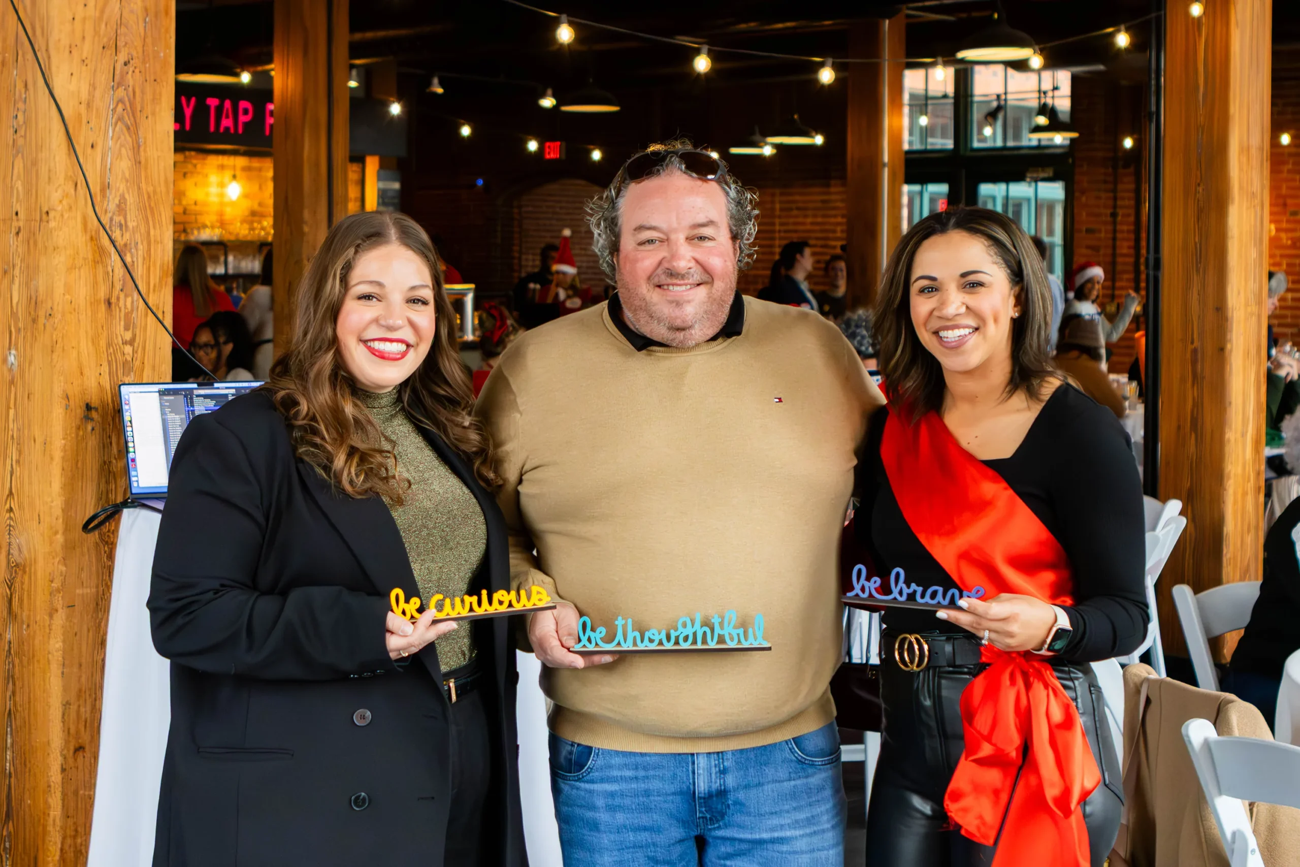 Kristen Kaestner holding the "Be Curious" award, Matt Anselm holding the "Be Thoughtful" award and Rachel Weis holding the "Be Brave" award.
