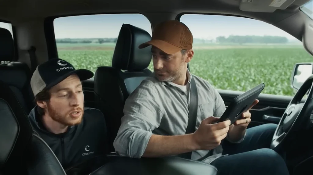 A driver showing a tablet to the passenger in the back seat.